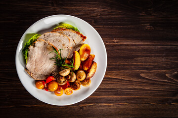 Roasted pork ham, champignons and fried potatoes on wooden table