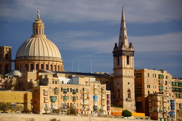 Architecture in the Maltese capital Valletta. Stone houses, multicolored balconies, church dome, sunny day.