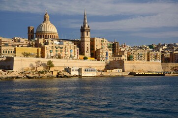 Fototapeta na wymiar Architecture in the Maltese capital Valletta. Stone houses, multicolored balconies, church dome, sunny day.