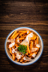 Penne with minced pork, tomato sauce, parmesan cheese, basil and vegetables served on wooden table
