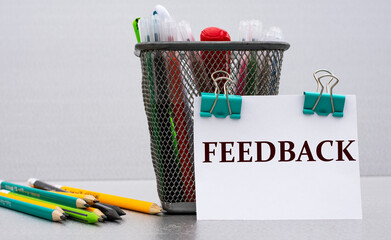 FEEDBACK - word on a white sheet with clips against the background of cans of pencils