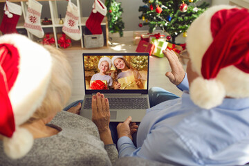 Grandparents in Santa hats video calling their little grandchildren on Christmas Day - obrazy, fototapety, plakaty