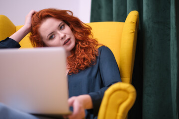 Redhead young woman using laptop at home. covid isolation. home office