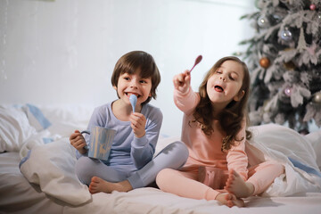 A family with children having fun on the bed under the covers during the Christmas holidays.