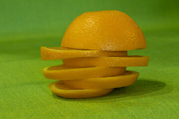 Cut orange slices in the form of a pyramid on a green cloth.