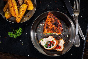 Stuffed chicken breast with baked potatoes on wooden background