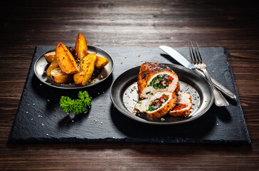Stuffed chicken breast with baked potatoes on wooden background