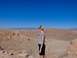 Blond woman on cliff in Atacama salt desert landscape, Chile