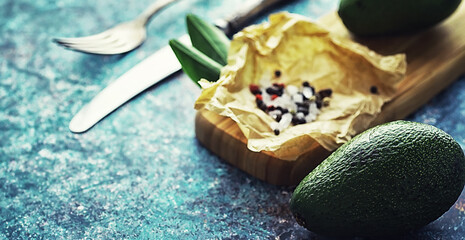 Avocado cooking recipes. Ripe green avocado on a wooden cutting board for serving.