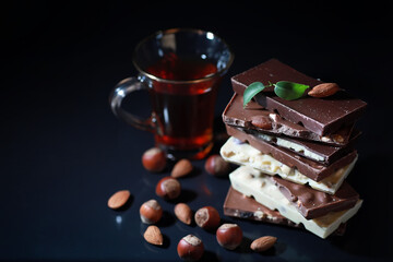 A bar of milk chocolate. Homemade milk chocolate with almonds and dried strawberries. Pieces of milk chocolate. Set of milk chocolate with tea.