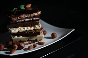 A bar of milk chocolate. Homemade milk chocolate with almonds and dried strawberries. Pieces of milk chocolate. Set of milk chocolate with tea.
