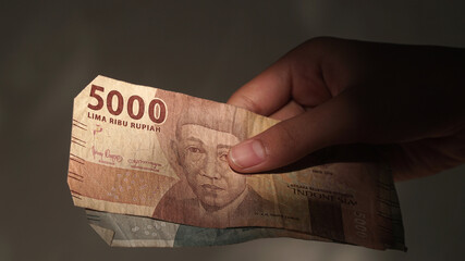 Indonesian rupiah banknotes, 5,000 rupiah, held by girls
