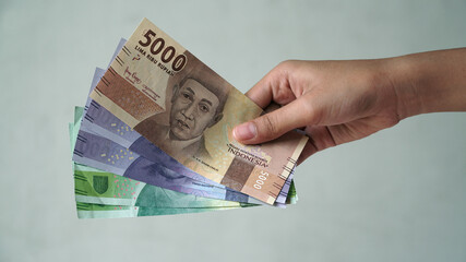 Indonesian rupiah currency, 5,000 rupiah, 10,000 rupiah, and 20,000 rupiah, is held by women's hands