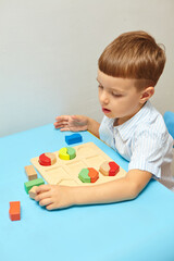 The boy is playing in his room. Learning shapes and colors. A child plays with a sorter. Educational logic toys for kid's. Montessori Games for Child Development.