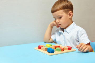 The boy is playing in his room. Learning shapes and colors. A child plays with a sorter. Educational logic toys for kid's. Montessori Games for Child Development.