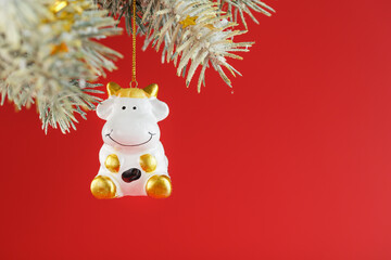 Figure of a Cow on a spruce branch, on a red background.