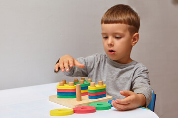 The boy is playing in his room. Learning shapes and colors. A child plays with a sorter. Educational logic toys for kid's. Montessori Games for Child Development.