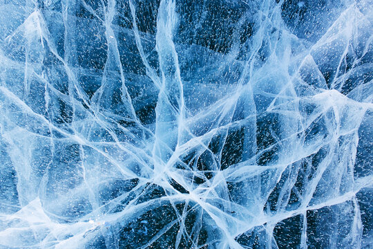 Natural cold background of ice. Beautiful blue ice of Lake Baikal with cracks. 