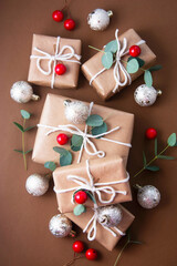 Christmas abstract background. Gift boxes wrapped with brown kraft paper decorated with eucalyptus, baubles and bokeh lights.