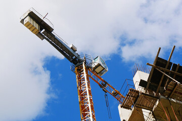 Сrane near building. Concrete building under construction. Industrial background.
