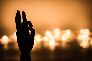 Silhouette of wooden hand with golden blurred lights background