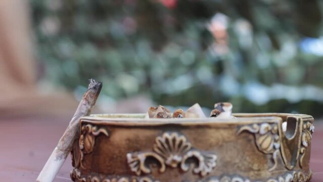 man smokes tobacco, old ashtray and cigarette butt that smoke, beautiful fingers putting the cigarette in the ashtray