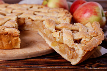 Traditional American Thanks Giving pie with whole organic apples, cinnamon sticks on wooden table. Homemade fruit tart baked to golden crust. Close up, copy space, top view, background.