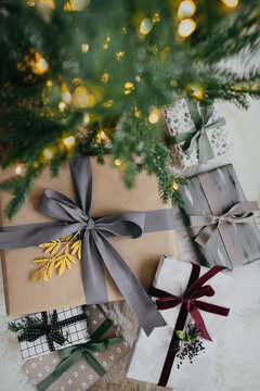 Stylish presents gathered under tree with Christmas lights on