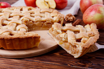 Traditional American Thanks Giving pie with whole organic apples, cinnamon sticks on wooden table. Homemade fruit tart baked to golden crust. Close up, copy space, top view, background.