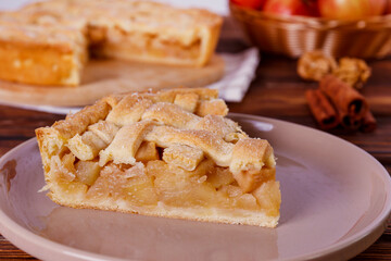 Traditional American Thanks Giving pie with whole organic apples, cinnamon sticks on wooden table. Homemade fruit tart baked to golden crust. Close up, copy space, top view, background.