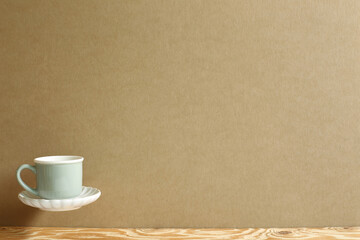 Mint green coffee cup floating on wooden table. Brown background copy space