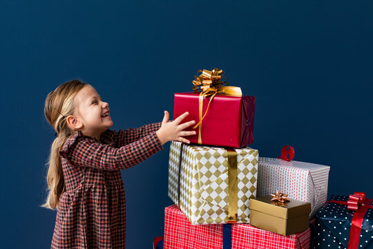 Adorable Toddler Girl Taking Present from a Pile of Boxes