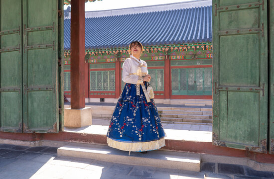 Woman wearing traditional Korean dress in front of Gyeongbokgung gate.