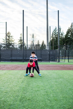 Asian Kids Playing American Football In An Outdoor Field