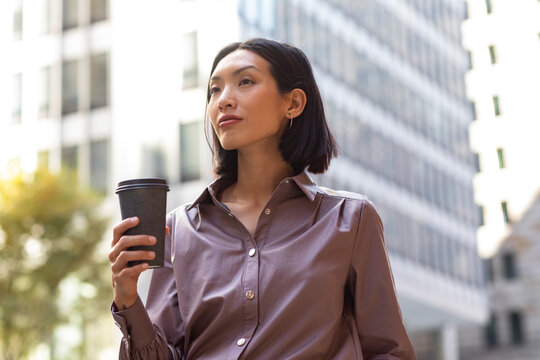 Asian Businesswoman Holding To Go Cup of Coffee