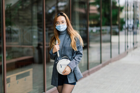Young fsian woman wearing face mask is standing at a domestic street. New normal covid-19 epidemic