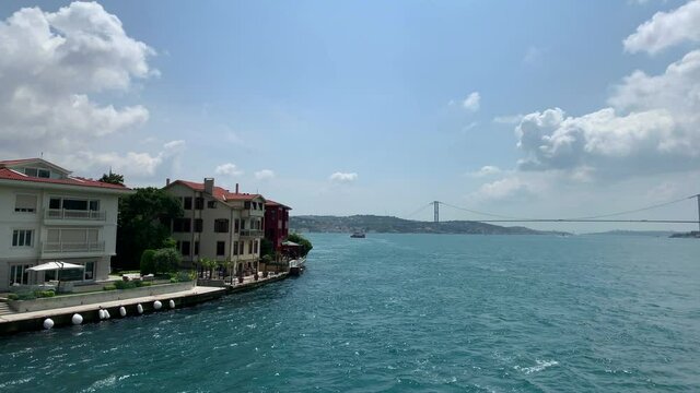Footage of luxury houses in upscale neighborhood called "Kandilli" by Bosphorus and bridge in Istanbul. It is a beautiful summer scene on cloudy summer day. Camera moves forward.