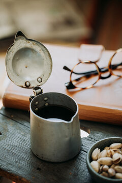 Dark coffee pot and pistachio bowl close to leather agenda