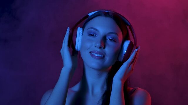 Portrait of charming young woman is dancing and enjoying music in big red headphones. Close up. Slow motion.
