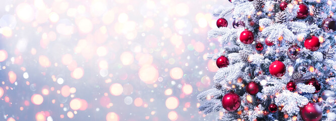 Abstract Holiday Background - Snowy Christmas Tree With Red Baubles With Shiny Defocused Lights
