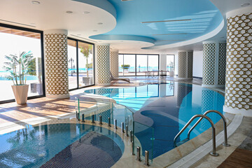 Indoor pool of luxurious hotel with different sections and big sea view windows. Close up, copy space, background.