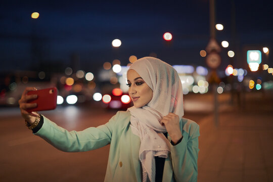 Young muslim women taking photos on the street.