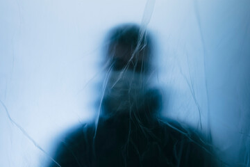 Man in face mask behind a protective barrier