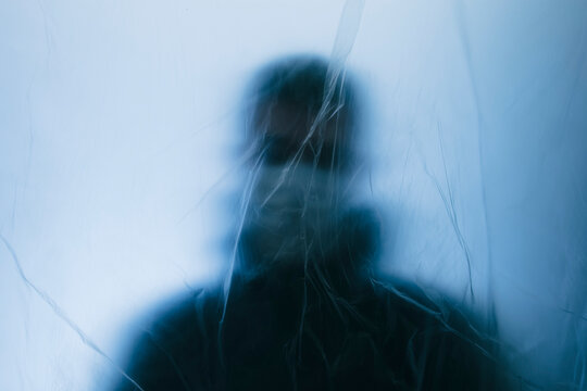 Man in face mask behind a protective barrier