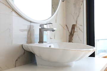 Close up shot of polished chrome one handle faucet and shell shaped wash basin in the kitchen. Copy...