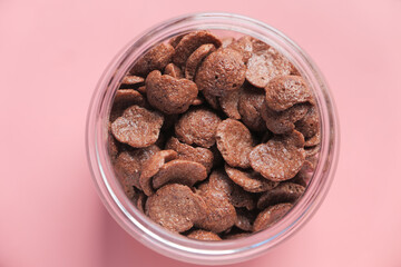  Top view of chocolate corn flakes in a bowl on pink 