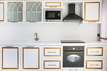 Fototapeta premium Modern black induction stove with hood, sink with copper faucet. Energy efficient electric hob with built-in oven at home kitchen . Close up, copy space, background.