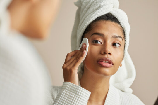 Woman applying cleasing lotion