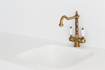 Close up shot of a vintage two handle faucet in a white minimalistic style kitchen. Copper retro...