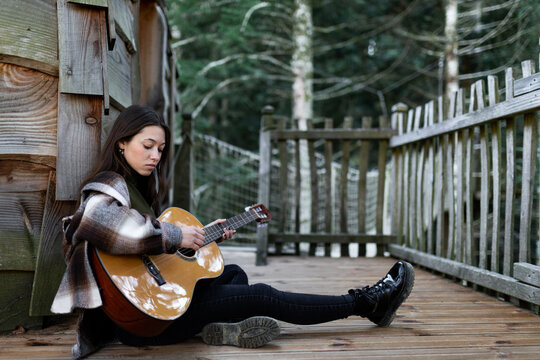 Young woman playing guitar in her cabin.